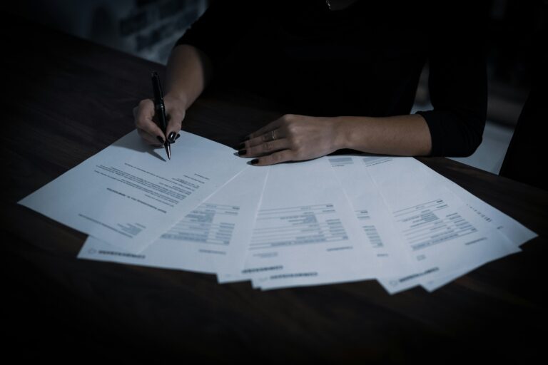 Hands of a person holding a pen over a pile of documents, symbolizing financial preparation and annual report filing in Estonia.