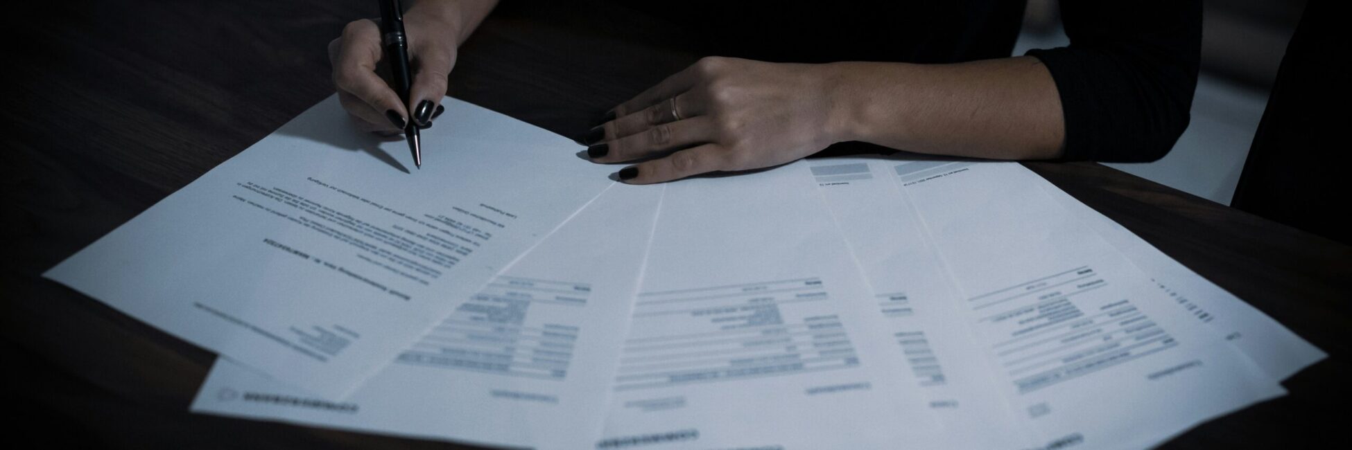 Hands of a person holding a pen over a pile of documents, symbolizing financial preparation and annual report filing in Estonia.